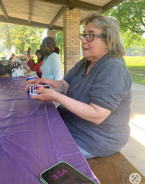 Person playing Uno cards under a park pavilion
